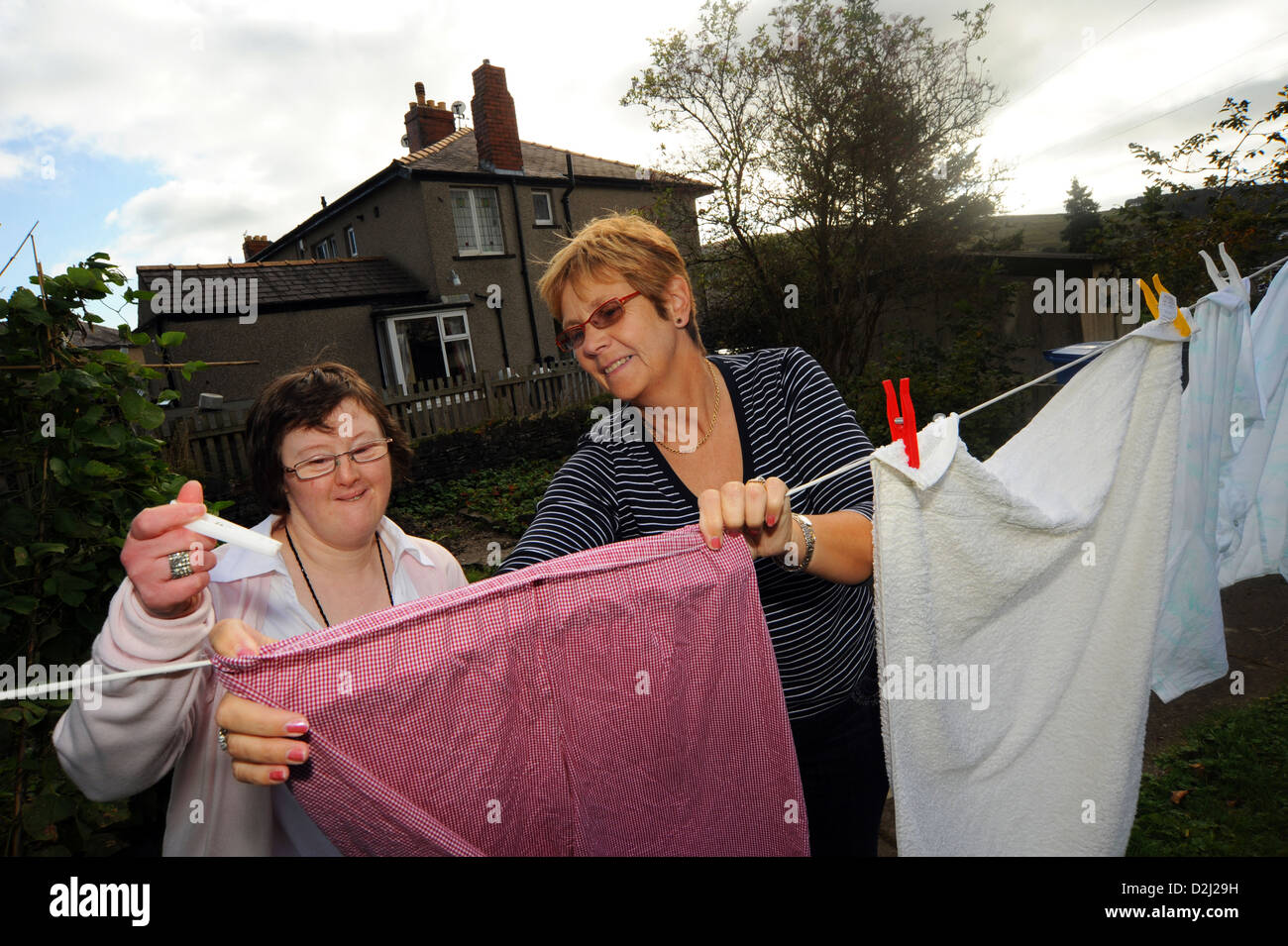 A young disabled  women hangs out her washing, she lives independently with help from her carer. Stock Photo