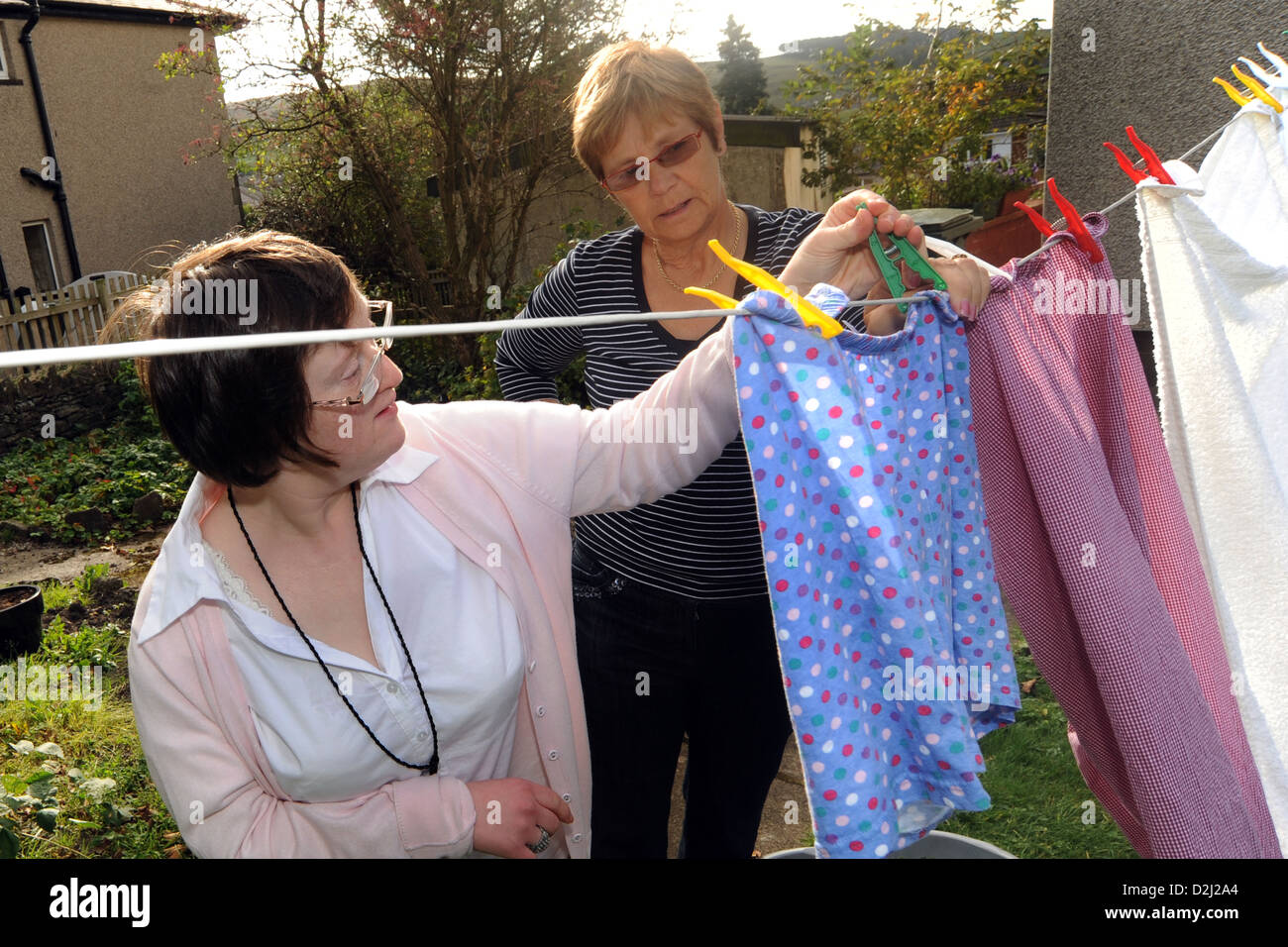 A young disabled  women hangs out her washing, she lives independently with help from her carer. Stock Photo
