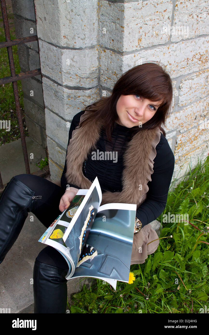 Beautiful smiling girl sitting outdoors with photo book Stock Photo - Alamy