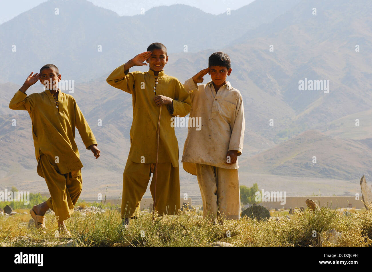 Afghan children salute the US Soldiers and Sailors from the side of the Nowabad-Khas Kunar Road in Afghanistan October 31, 2010. The road, which was built over the course of the previous year was officially opened during a ribbon-cutting ceremony earlier that day. Stock Photo