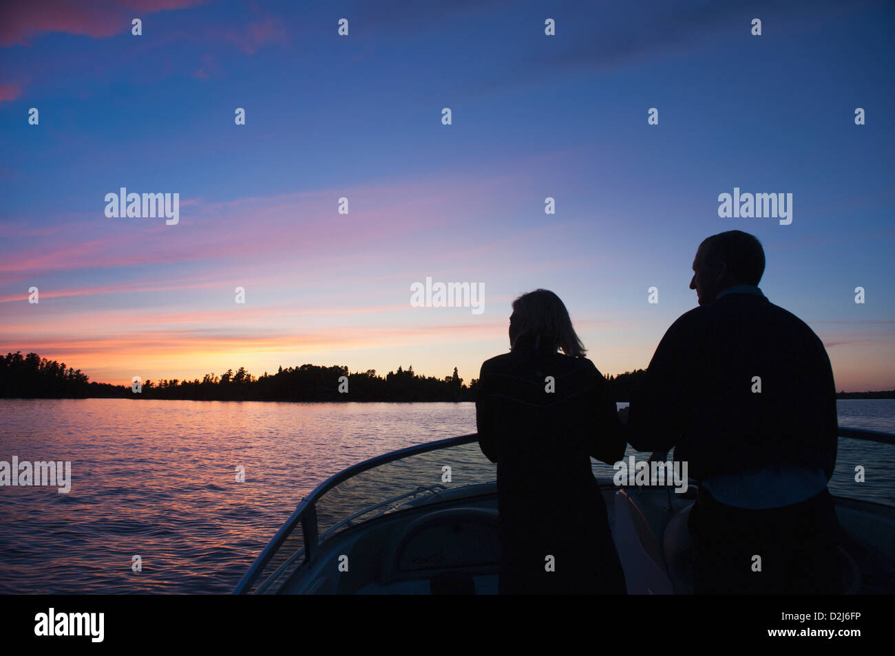 Middle aged couple travelling by motorboat in the lake of the woods at ...