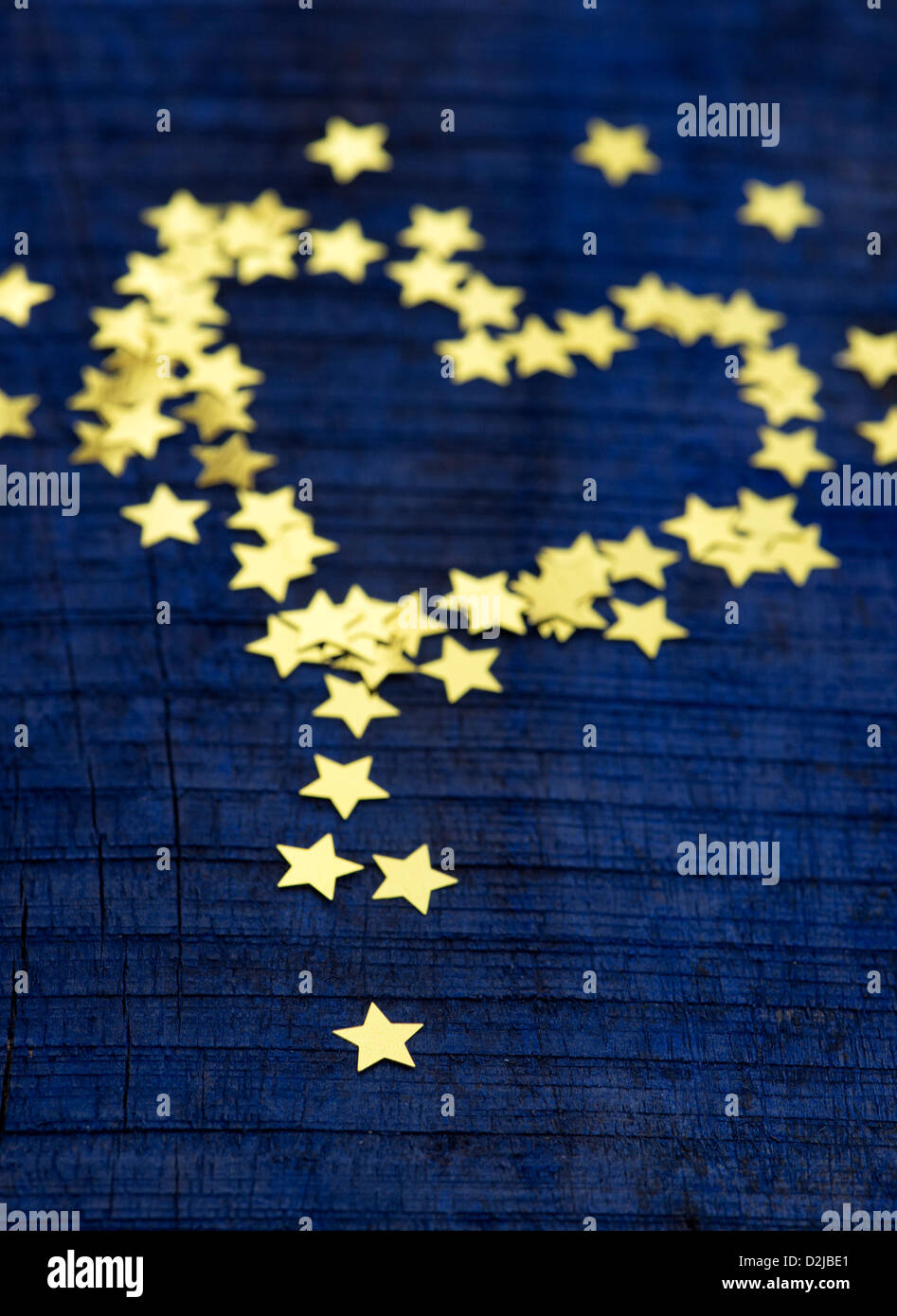 Shiny gold stars in a heart shape on a dark blue wood background Stock Photo