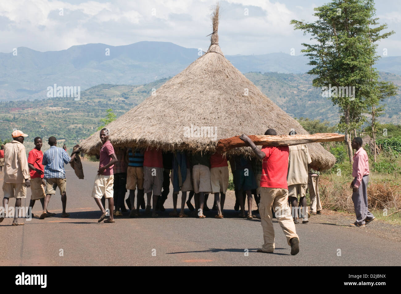Group of men carrying thatched roof down highway Stock Photo