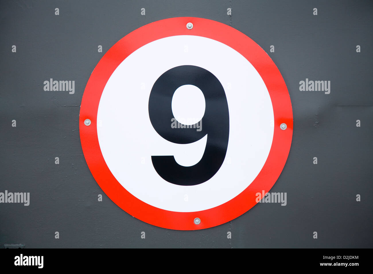 Sign showing the numeral / number 9. Based on a road traffic sign this is actually an unusual house number sign. Stock Photo