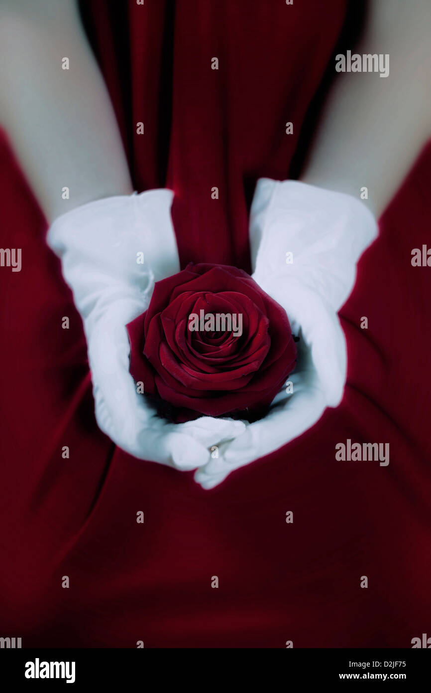 a woman in a red dress with white gloves is holding a red rose on her ...