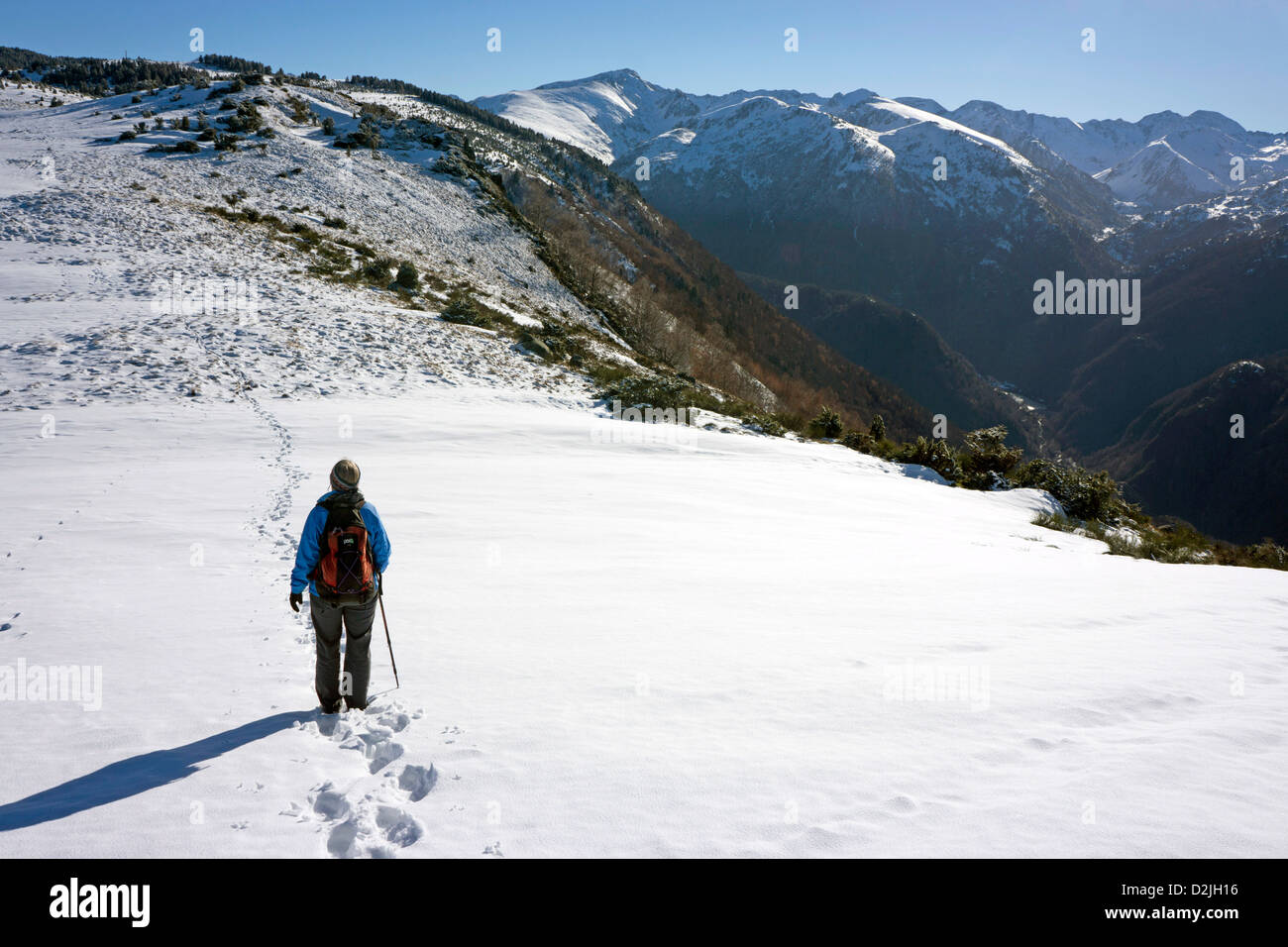 Walker in blue on snow slope, French Pyrenees Stock Photo