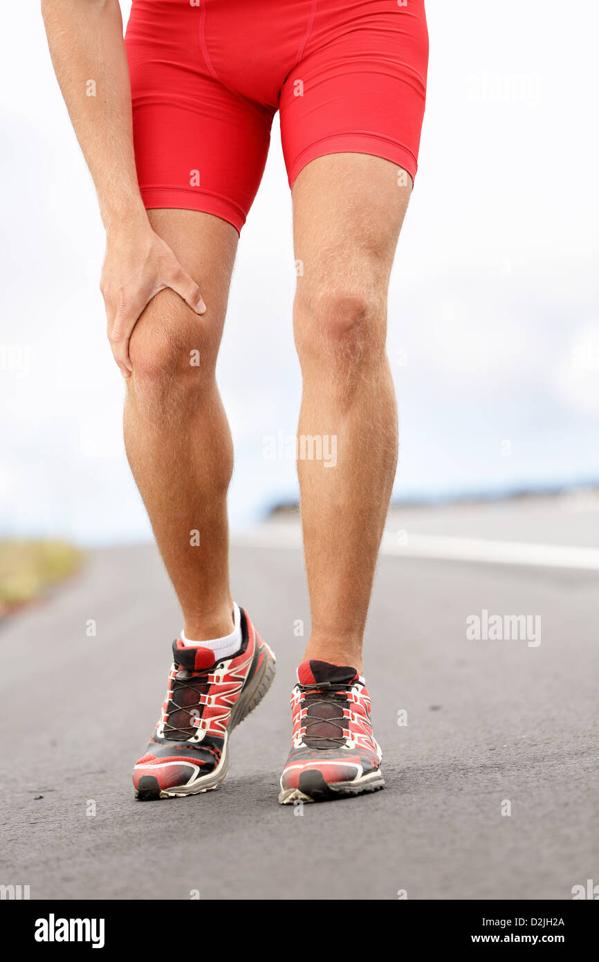Low section of male runner having knee problems during exercise Stock