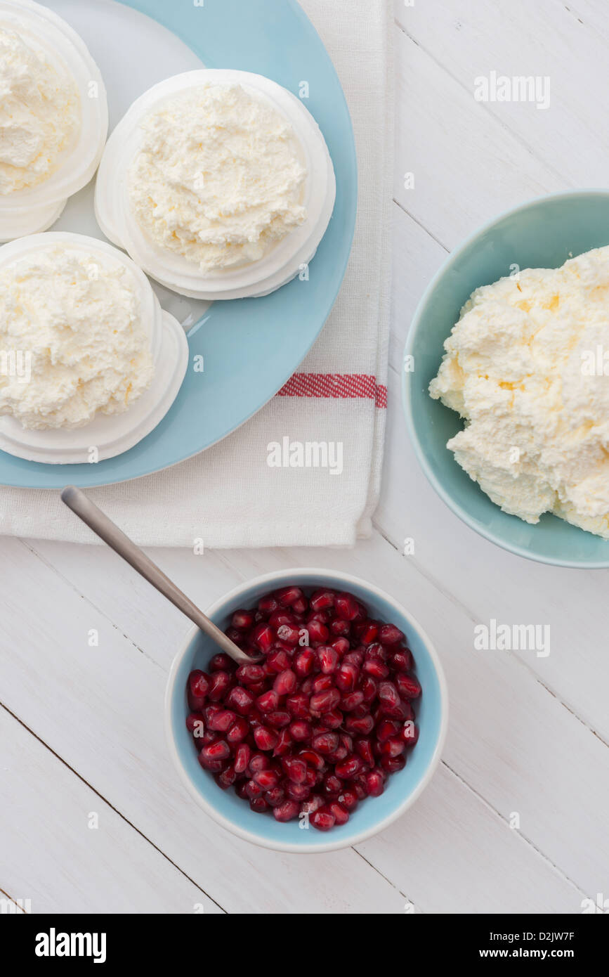 Meringue nests with fresh whipped cream and pomegranate seeds. Stock Photo