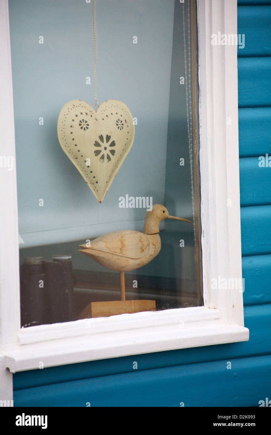 bird carving and hanging heart in window of beach hut at Hengistbury Head, Dorset in January Stock Photo
