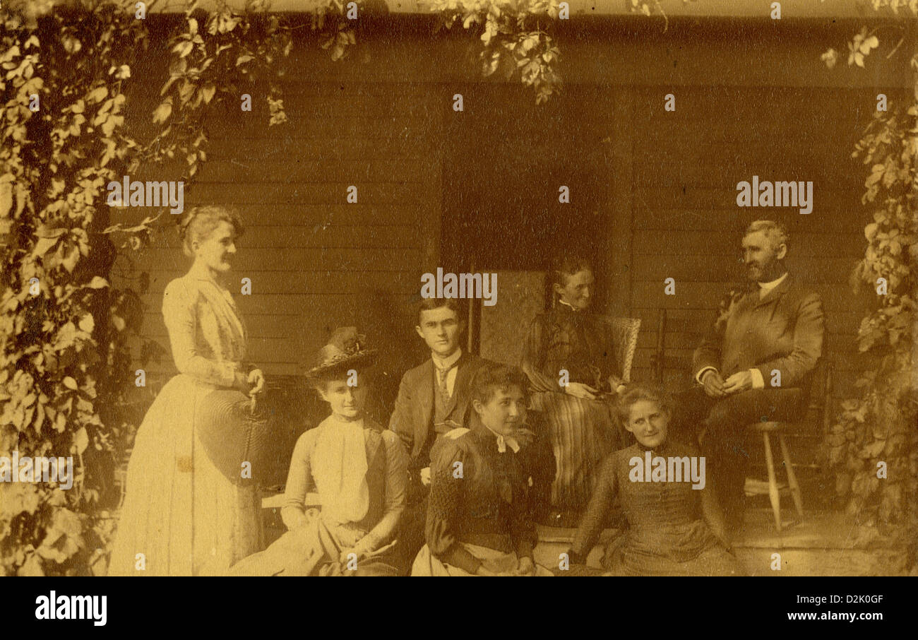Circa 1890 cabinet card photograph, Victorian family on porch of house with vines. Stock Photo
