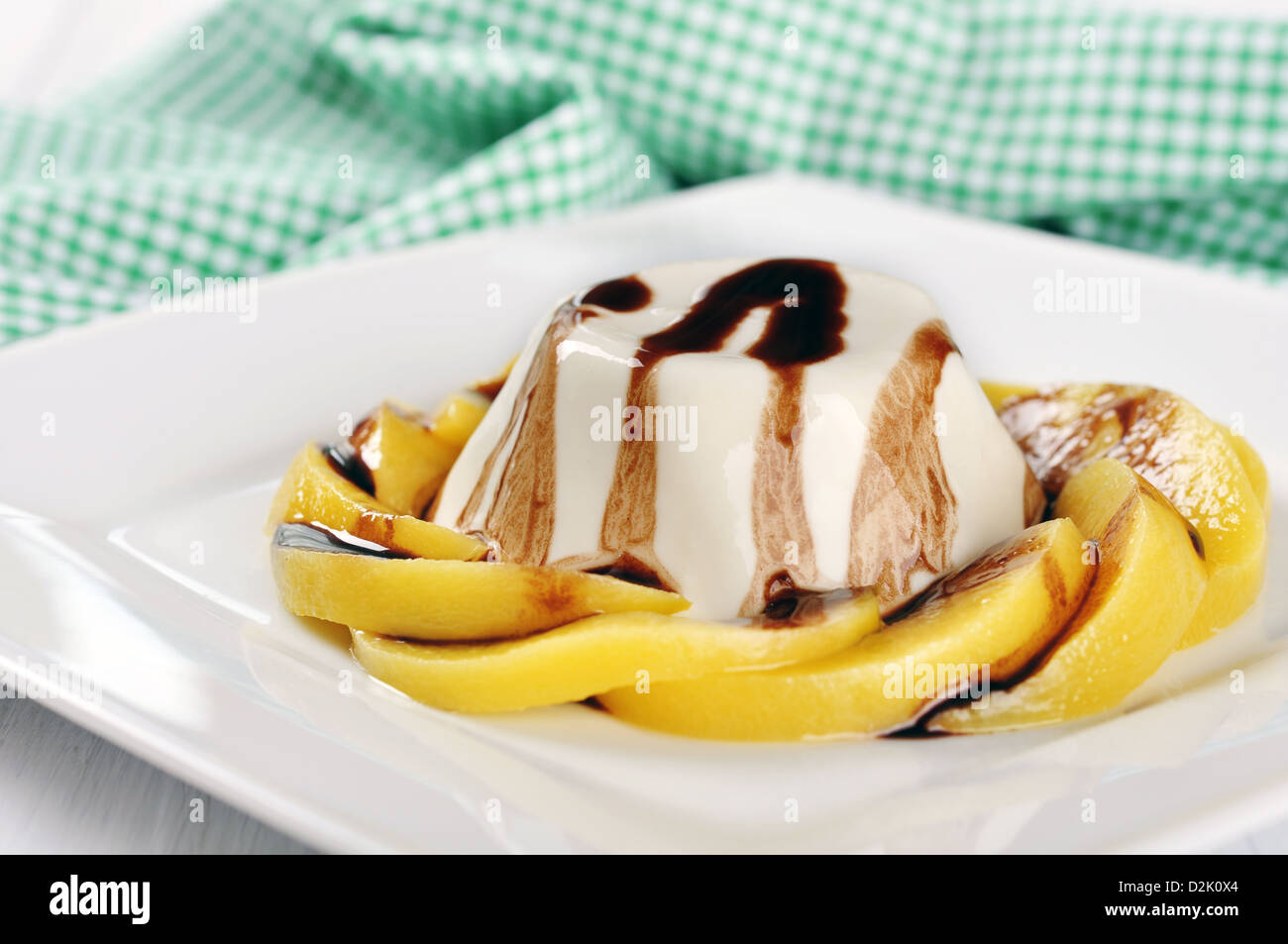 Italian dessert Panna cotta with peach and chocolate sauce on the plate Stock Photo