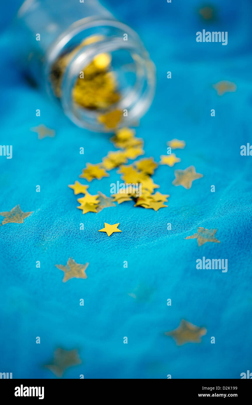 Shiny gold stars coming out of a glass jar on blue star shawl Stock Photo