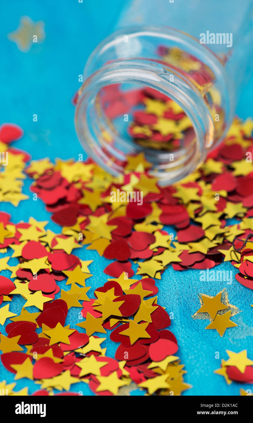 Shiny red love hearts and gold stars coming out of a glass jar on blue star shawl Stock Photo