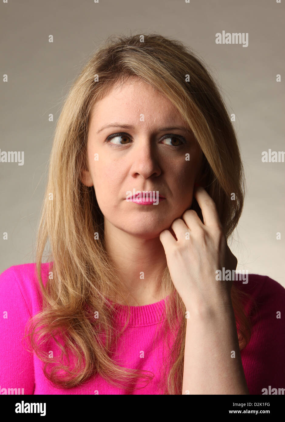 Pensive young blond woman with hand on face looking away, January 23, 2013, © Katharine Andriotis Stock Photo