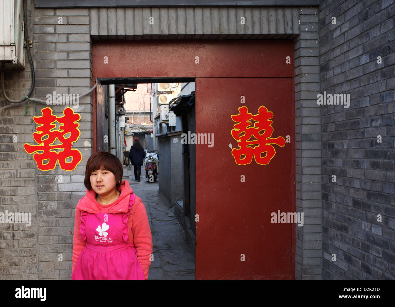 A lady walks past Double Happiness decoration which is for a wedding at a doorway in central Beijing, China. 26-Jan-2013 Stock Photo