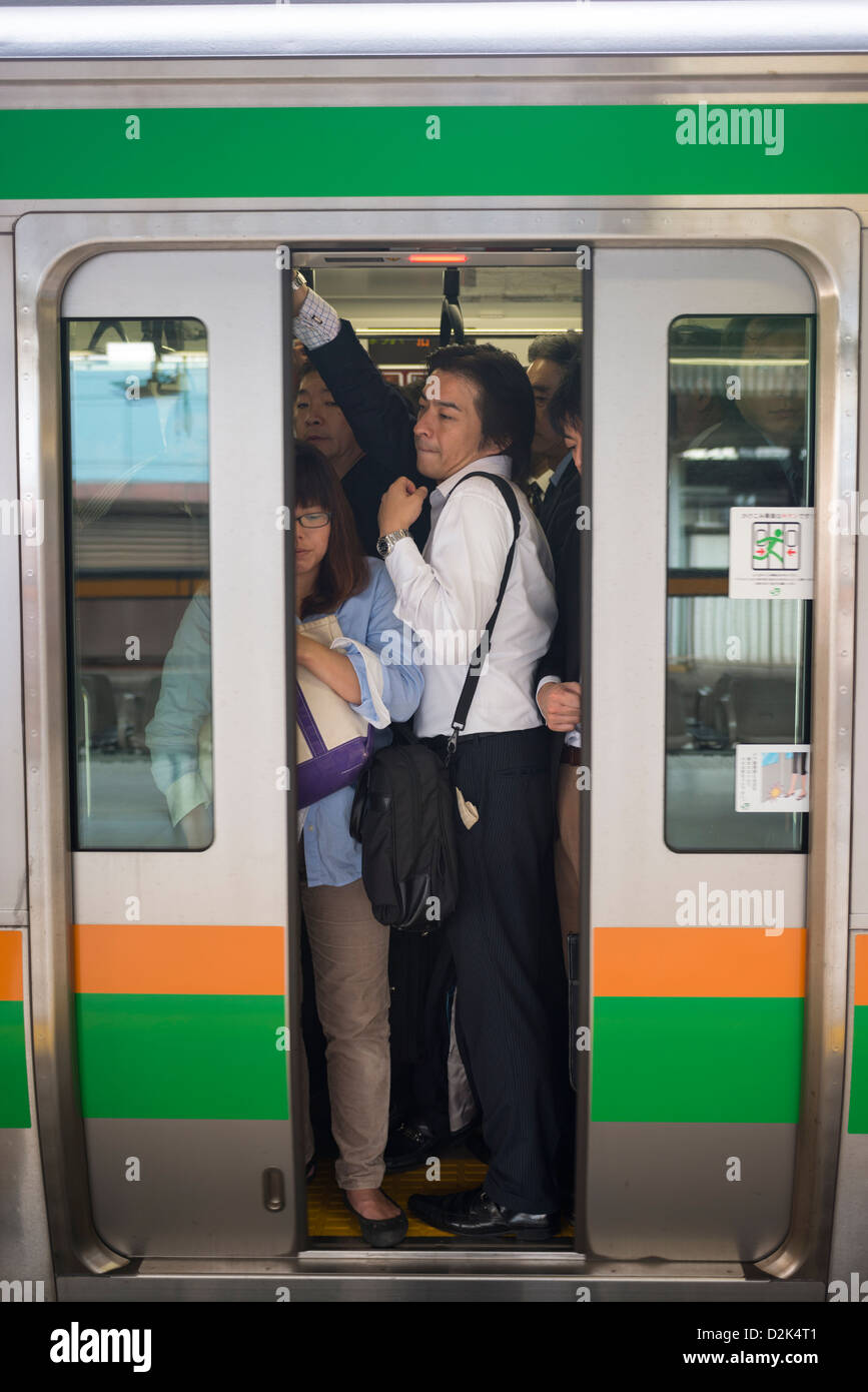 Workers crowded during rush hour onto a train in Tokyo Japan Stock Photo