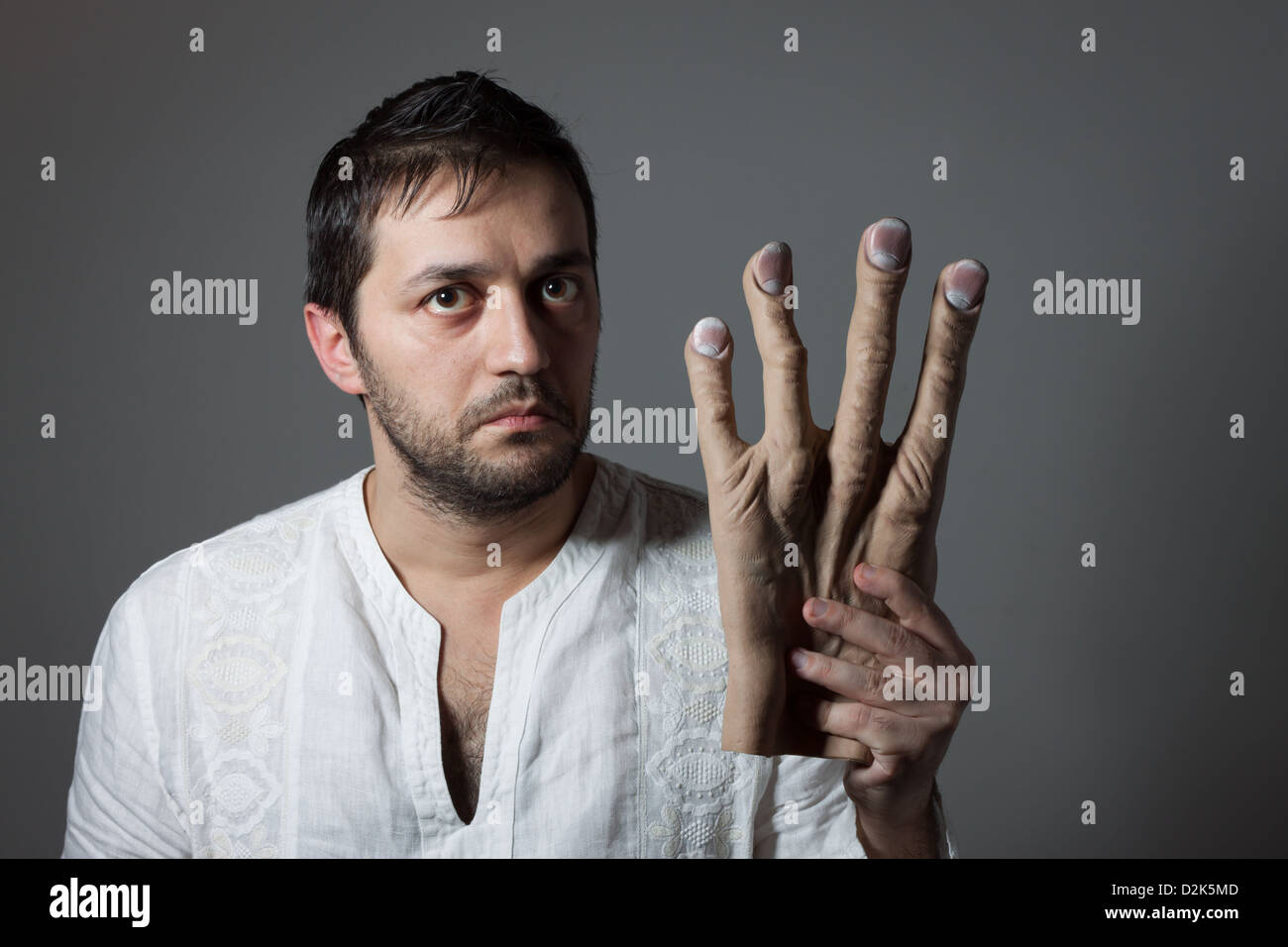 Young bearded man with interrogative expression on his face holding a huge mock hand Stock Photo
