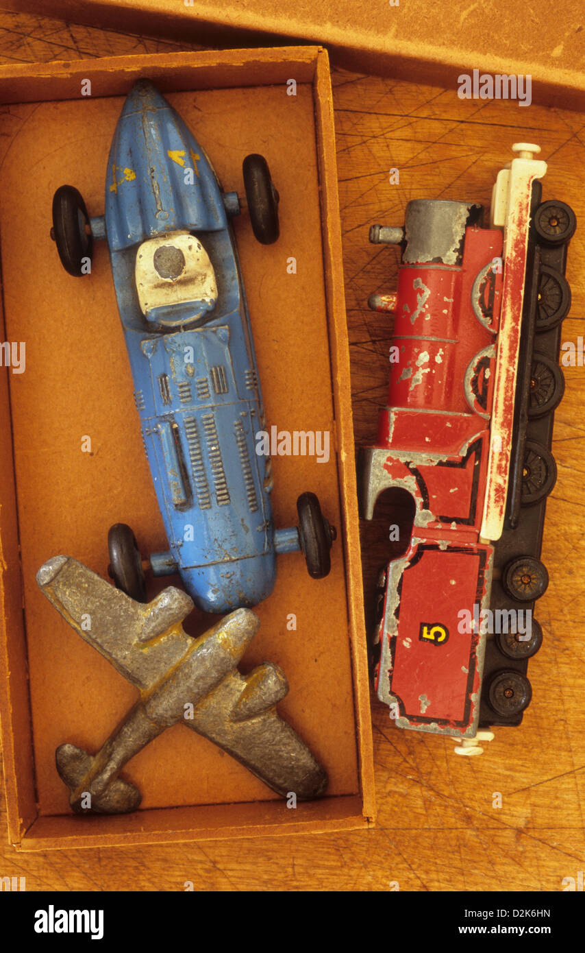 Small cardboard box with battered lead or diecast metal models of aeroplane racing car and steam locomotive Stock Photo