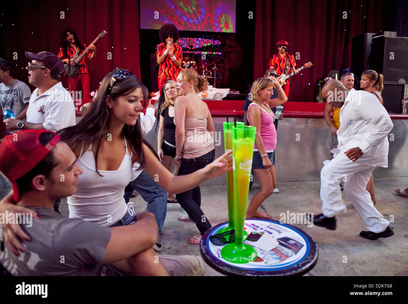 a girl on boyfriends lap reaches for her drink at Carnaval Court Bar &  Grill, dancing drinking and band in the afternoon Stock Photo - Alamy