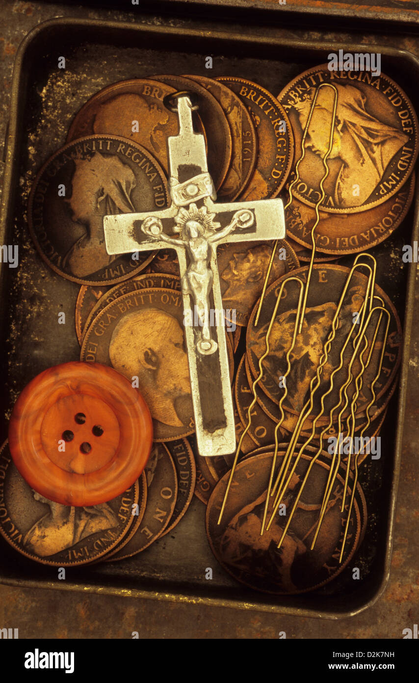 Tin containing silver and black crucifix orange button hairgrips and old British Victorian and Edwardian pennies Stock Photo