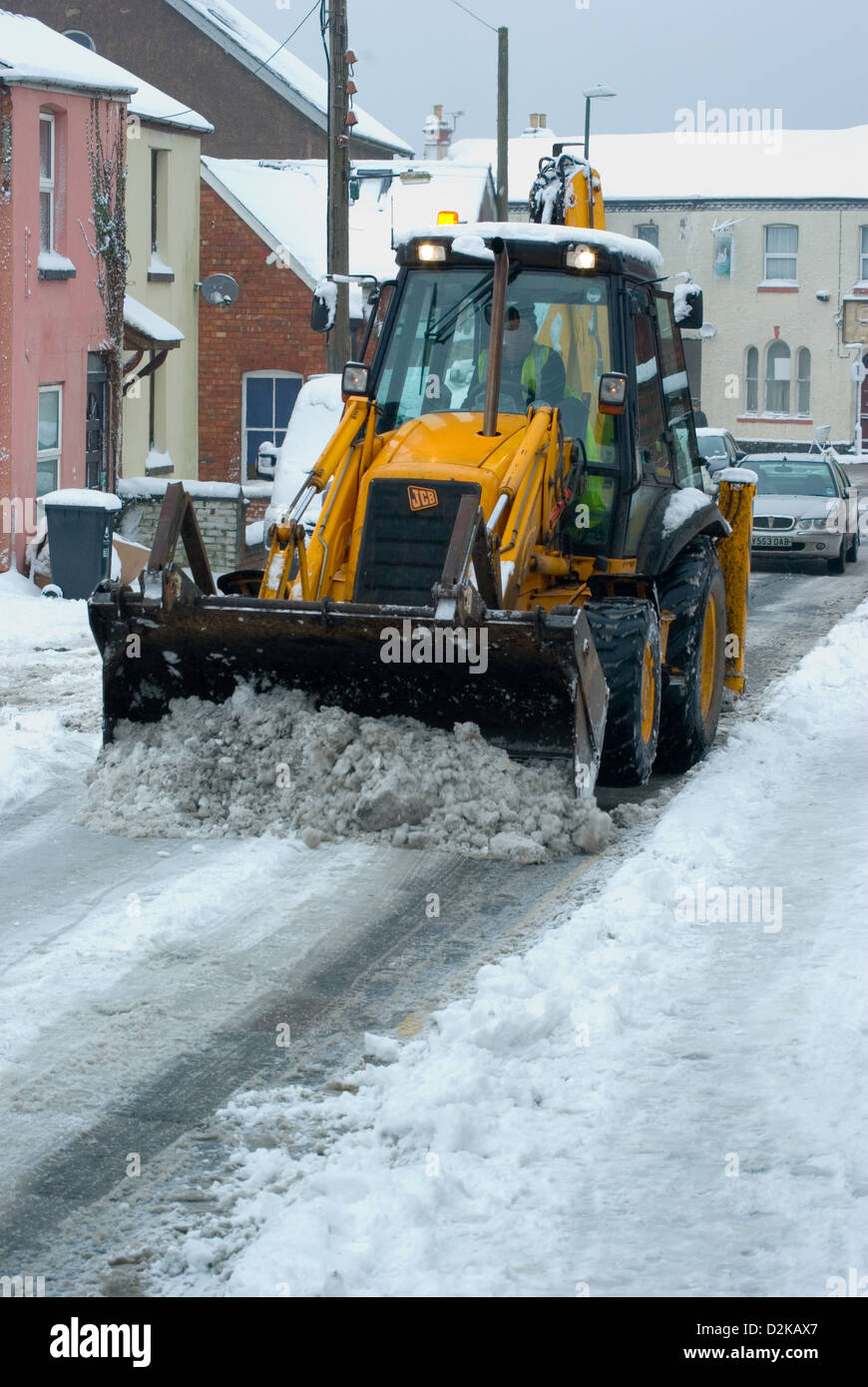 Clearing small side streets of snow with a JCB during a typical UK / British winter. Stock Photo