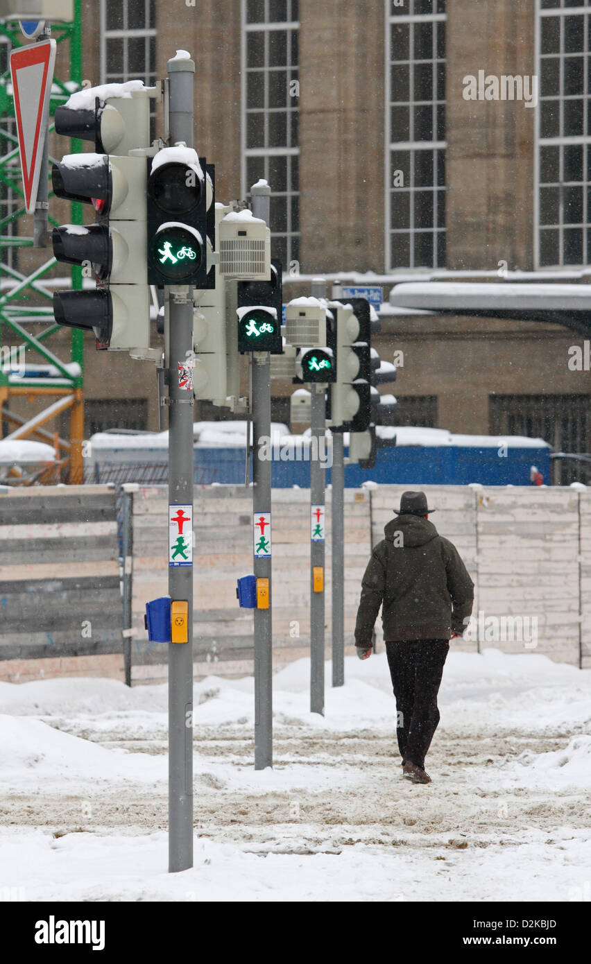 Leipzig, Germany, a man with a hat in the snow goes in green over a traffic light Stock Photo
