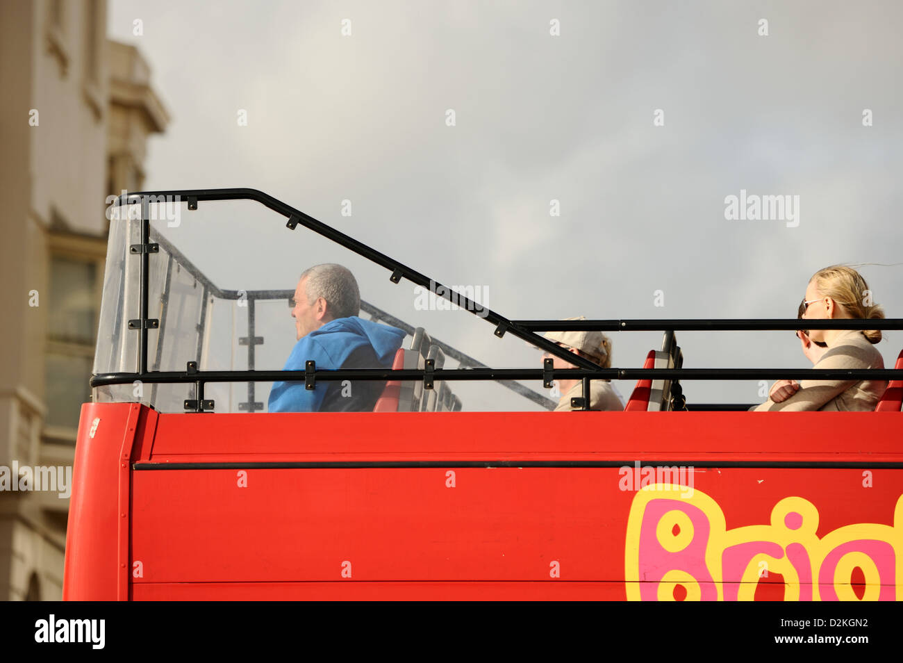 Passengers on the top deck of an open-top bus travel along Kinsway, Hove Stock Photo