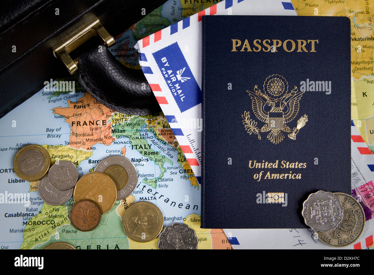USA passport, foreign coins and briefcase sit on a world map for an international business travel concept. Stock Photo