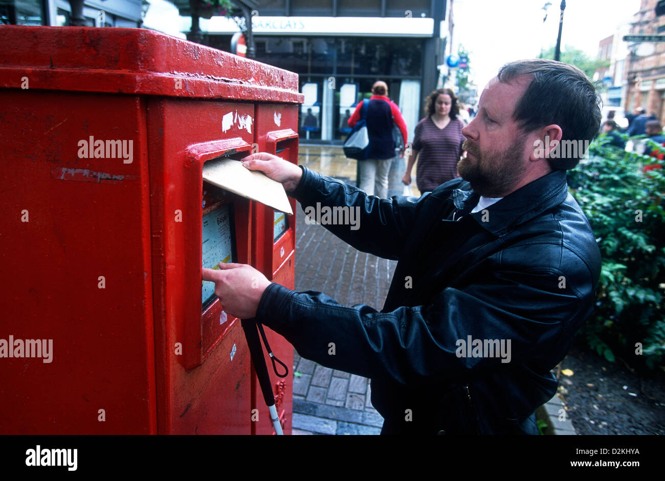 Blind man posting a letter, High Street, Lincoln, UK. Stock Photo