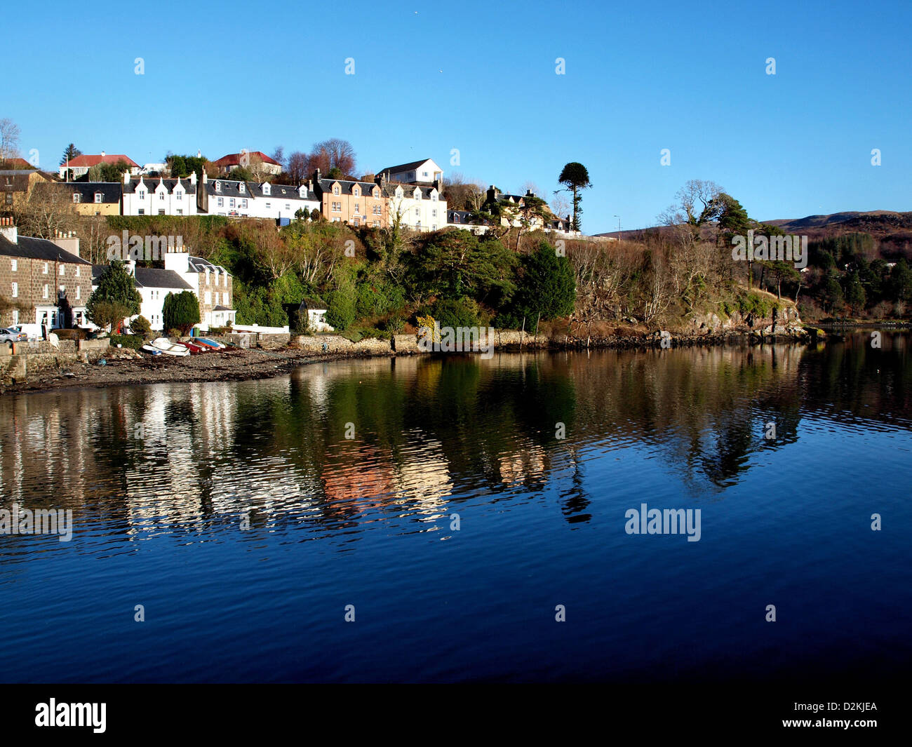 Houses above the harbour of Portree, in the Scottish Isle of Skye, reflected in the water. Stock Photo