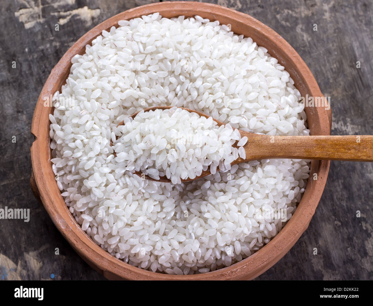 Rice on bowl and wooden spoon on old table Stock Photo