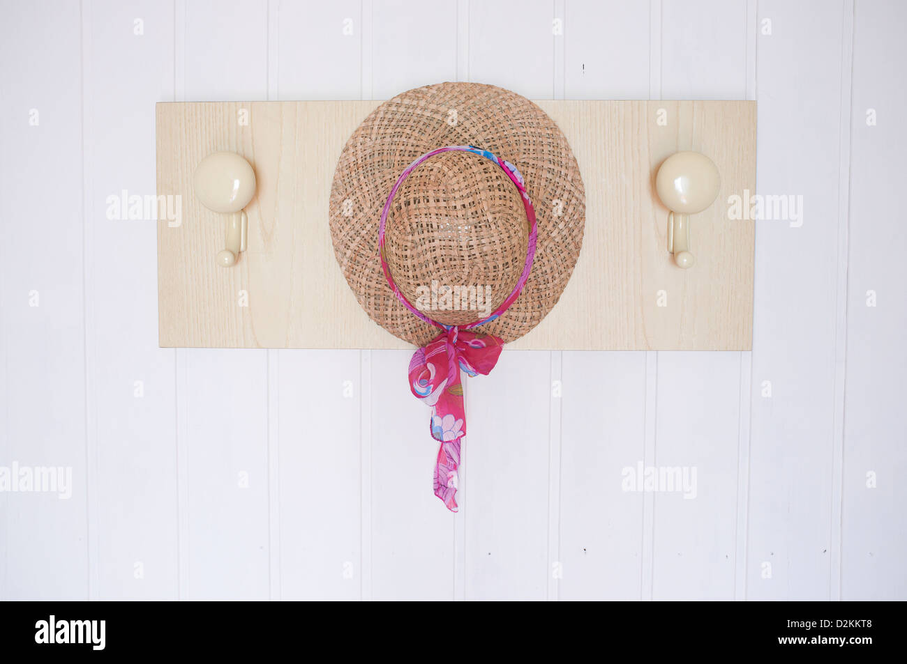 ladies hat hanging against white wooden wall Stock Photo