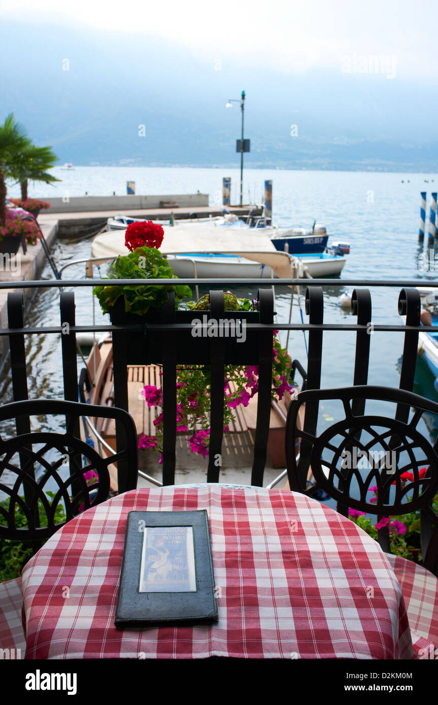 Menu sitting on table over looking Limone harbour, Lake Garda Stock Photo