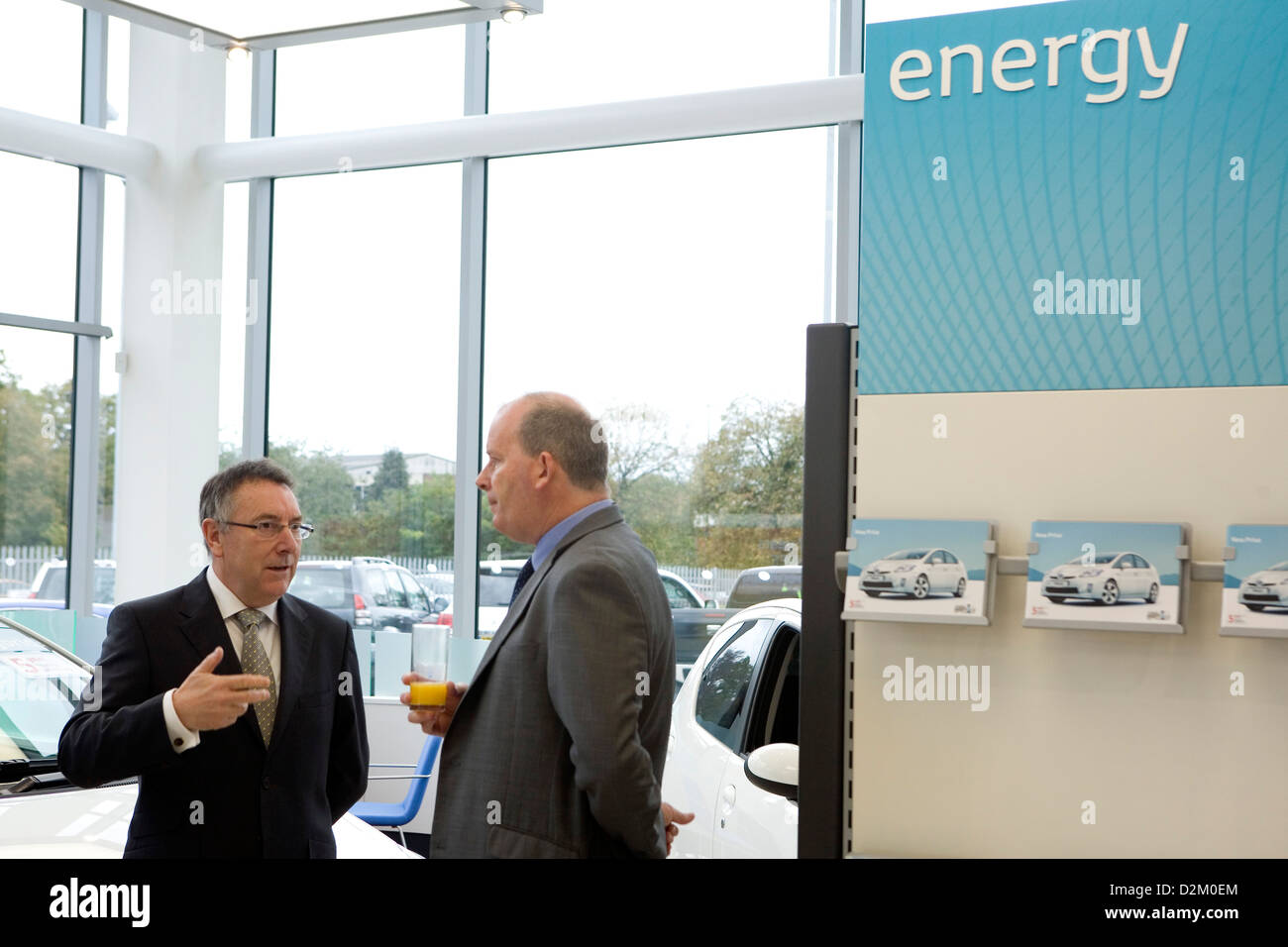Businessmen stand next to an energy sign in a newly built car dealership in the UK. Stock Photo