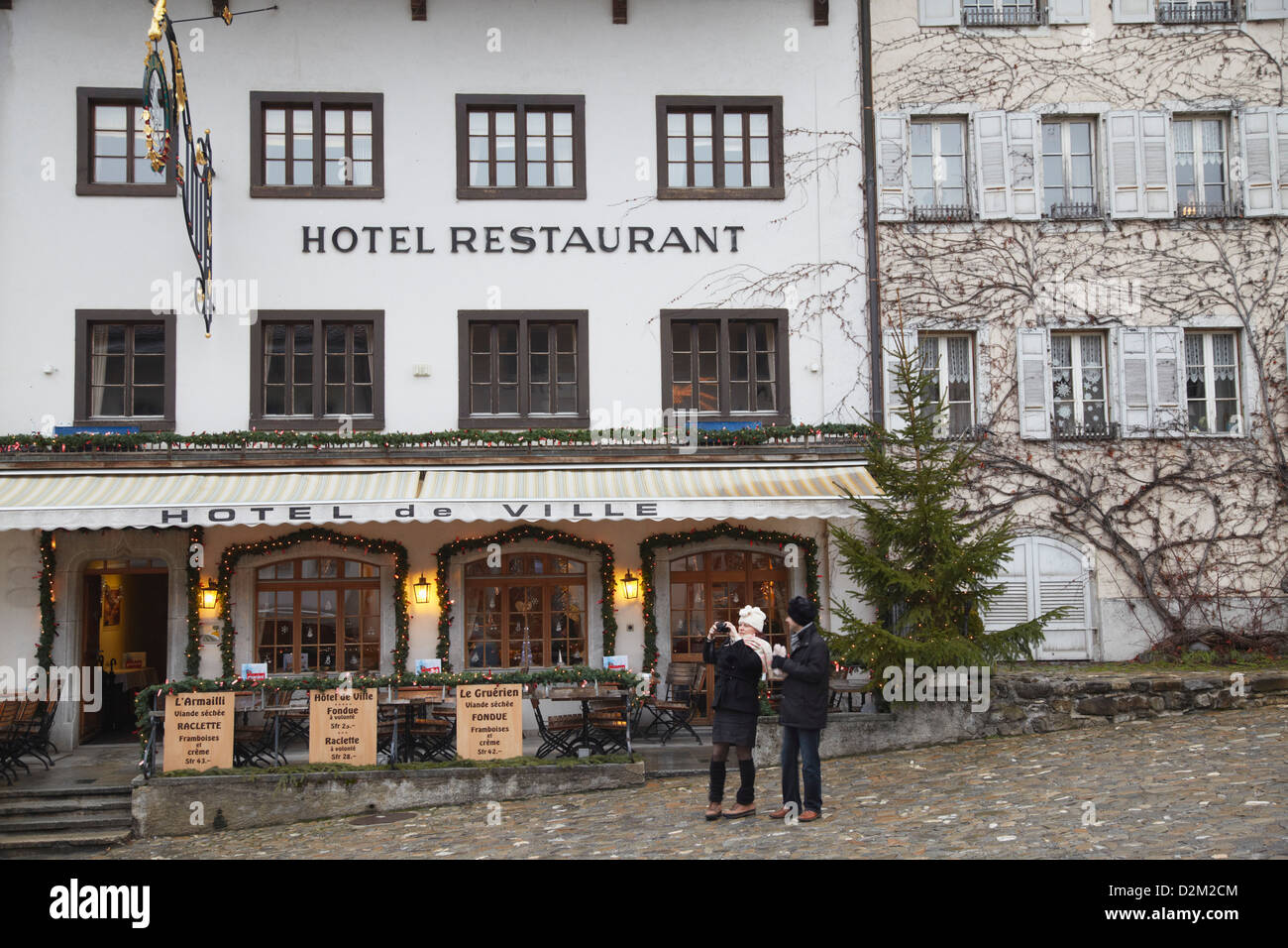 Couple standing outside restaurant, Gruyeres, Fribourg, Switzerland Stock Photo