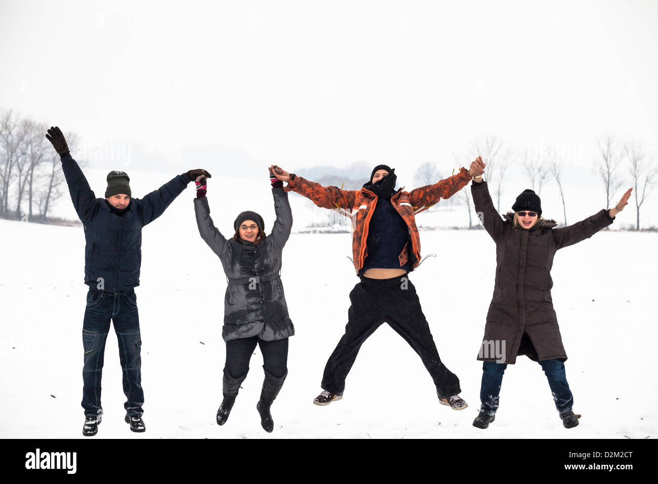 Group of young happy people jumping in snow and enjoying winter. Stock Photo