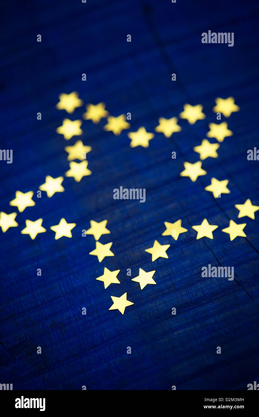 Shiny gold stars in the shape of a 5 pointed star on a dark blue wood background Stock Photo
