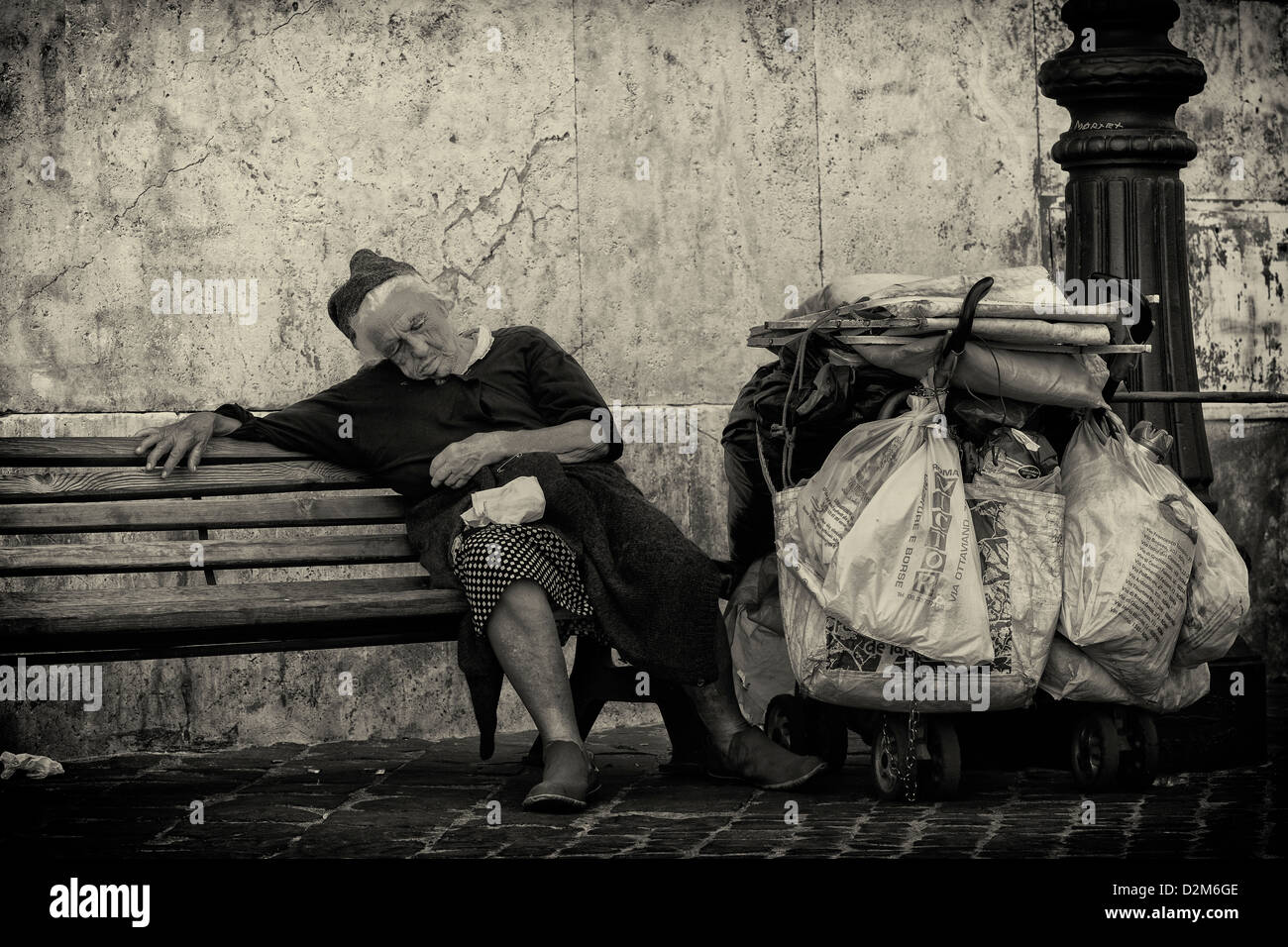 Old lady tramp on bench in Rome, Italy. Stock Photo