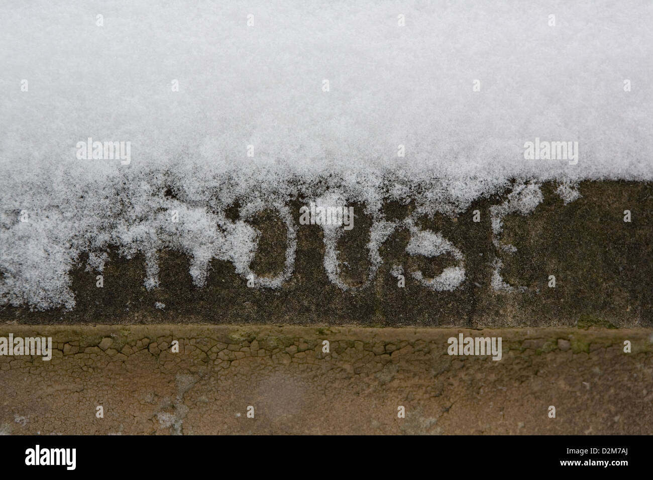 Snow covered stone pillar/gate post with the word House carved into it. Stock Photo