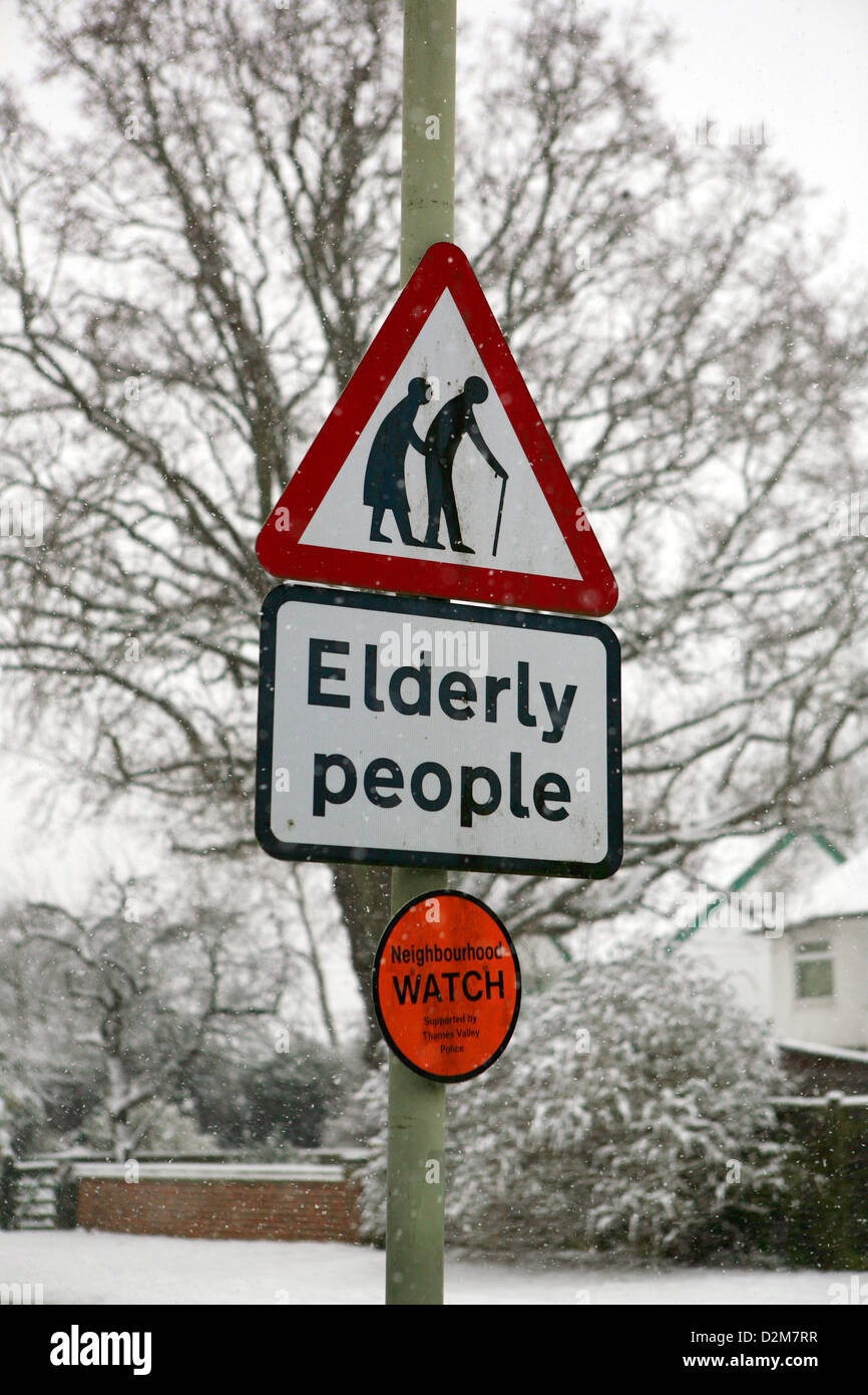 Kinneir & Calvert Elderly people warning road sign and Neighborhood Watch sign in Britain, bad weather snow all around the sign. Stock Photo