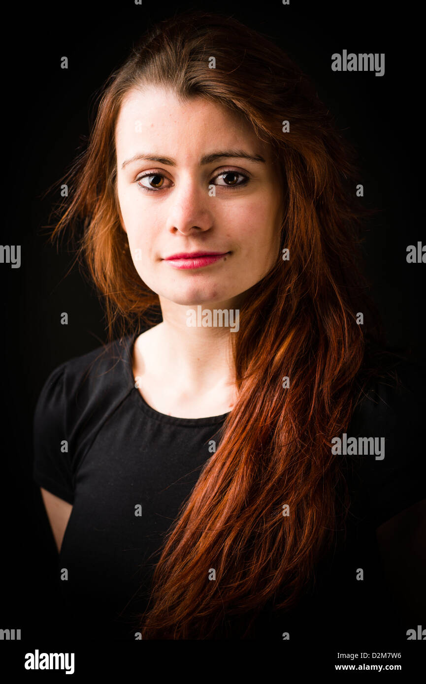 A nineteen year old girl young woman, with long brown hair, UK, black background Stock Photo