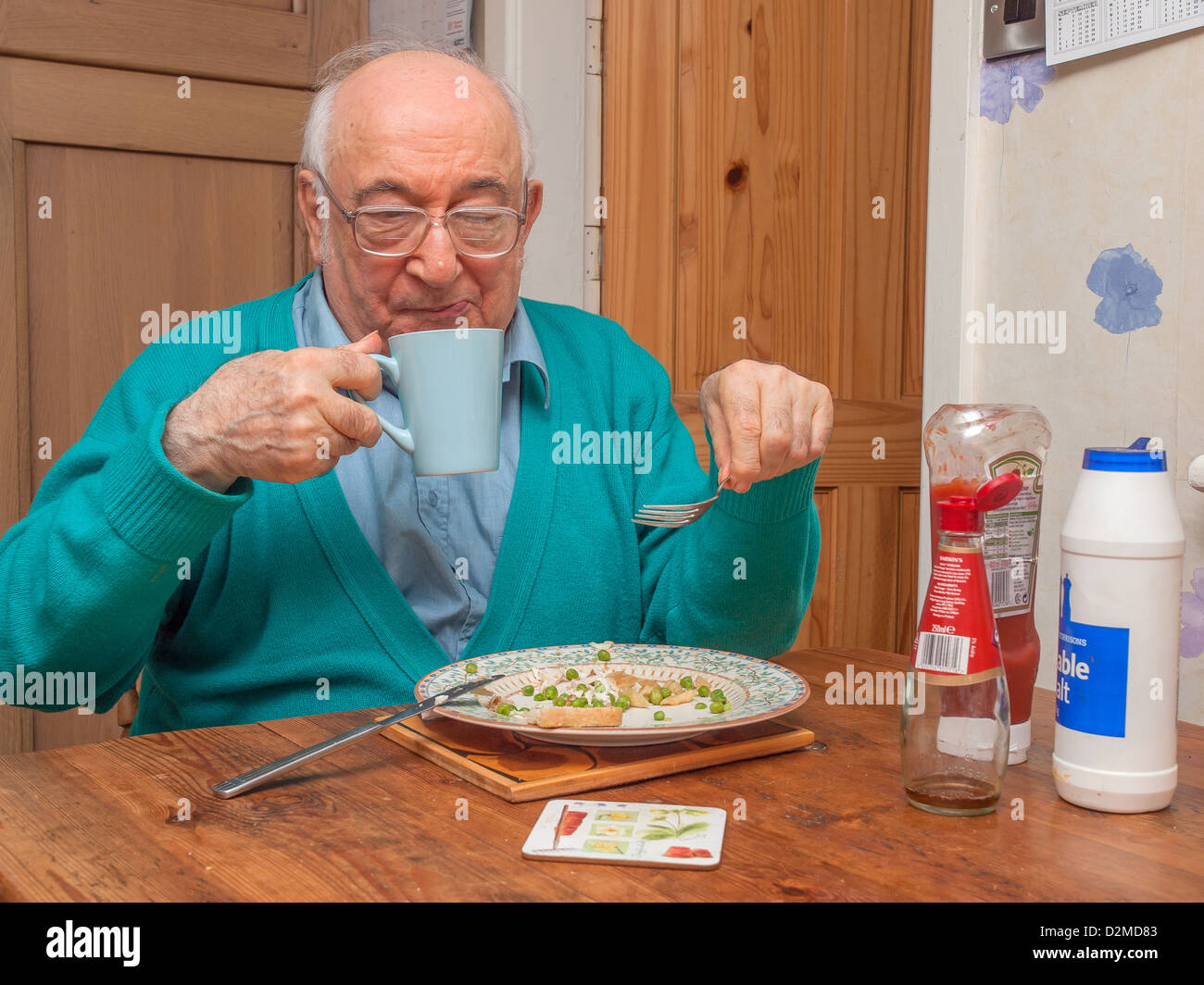 elderly man sat at dining table eating and drinking Stock Photo Alamy