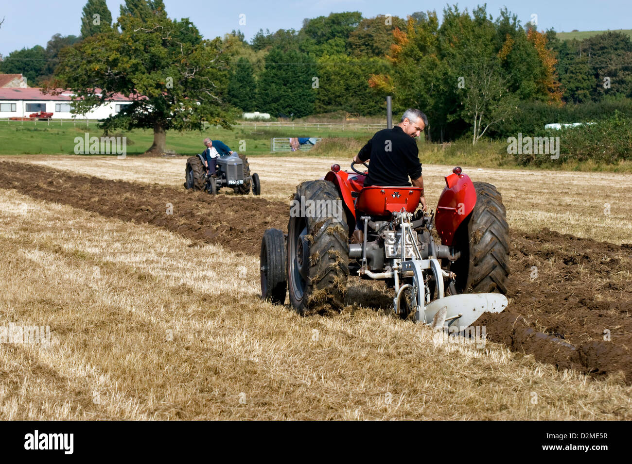 Tractor enthusiasts in a renovated red Massey Ferguson 35 tractor & a renovated grey Ferguson T20 tractor in a ploughing match Stock Photo