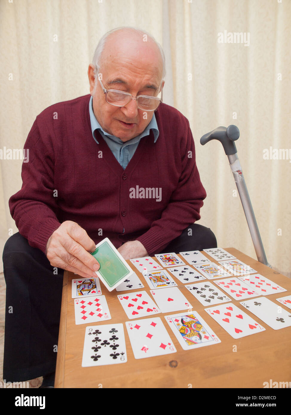 elderly seated man playing cards on his own Stock Photo
