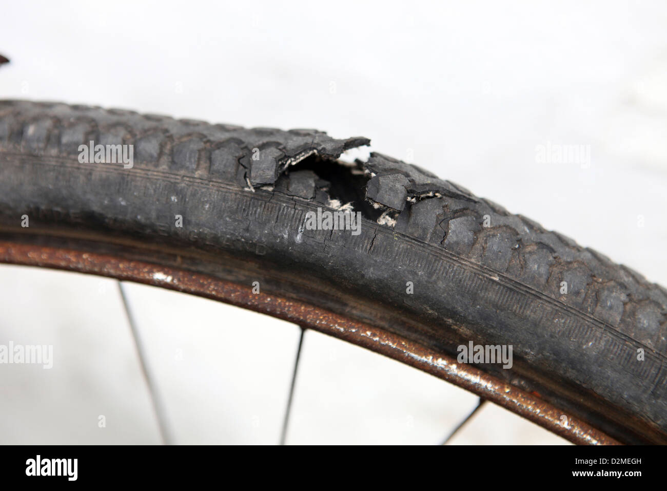 Rusty Bicycle wheel, it's old rubber tyre (tire) has perished and has a hole. Stock Photo
