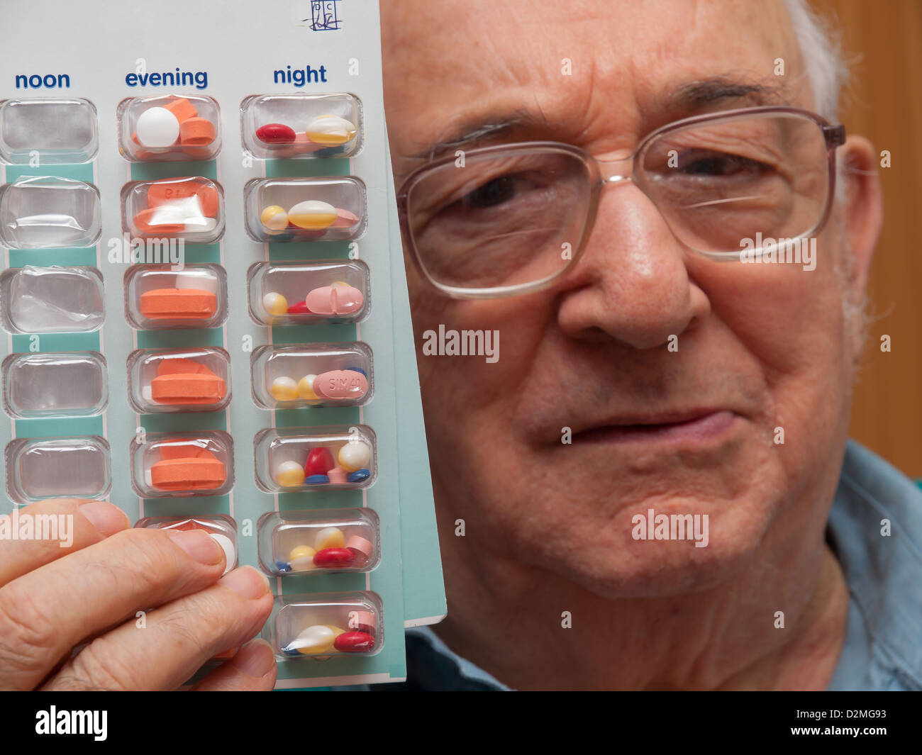 elderly man showing blister pack of tablets holding close to face Stock