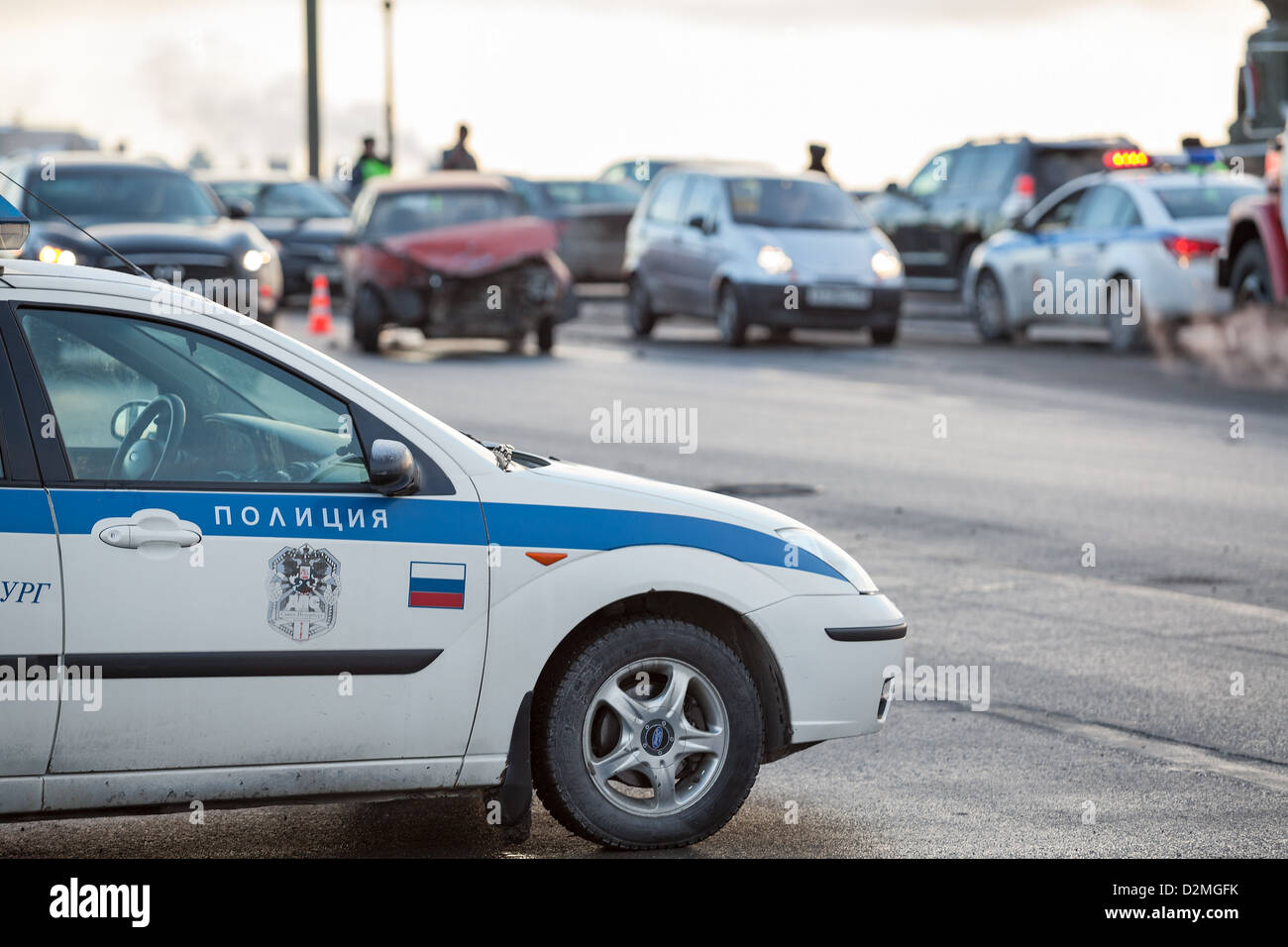 Russian police car is at the accident site with crashed car on background in St. Petersburg, Russia. Frontal impact. Stock Photo
