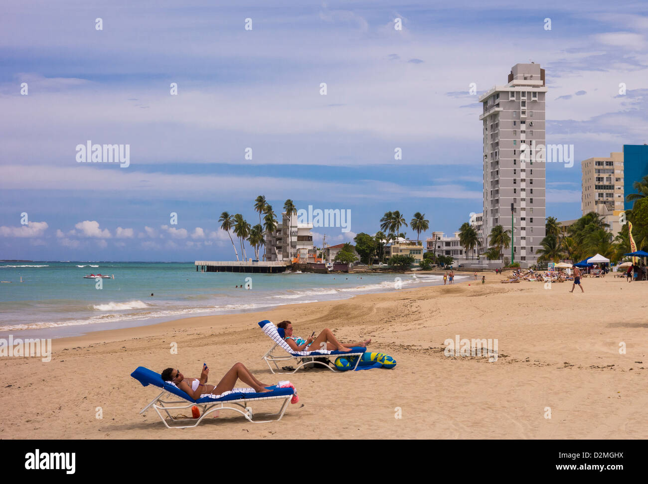 SAN JUAN, PUERTO RICO - Women tourists looking at smart phones on beach at Isla Verde. Stock Photo