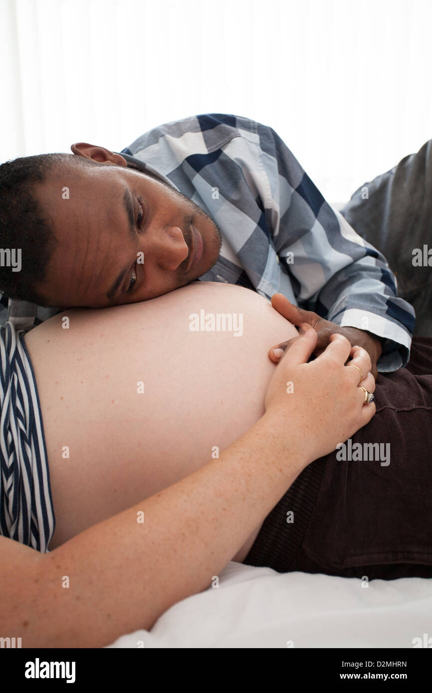 pregnant white female and black male listening to baby's heartbeat Stock Photo