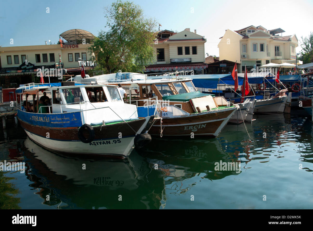 Small white tourist boats with red turkish flags tied up in front of restaurants Stock Photo